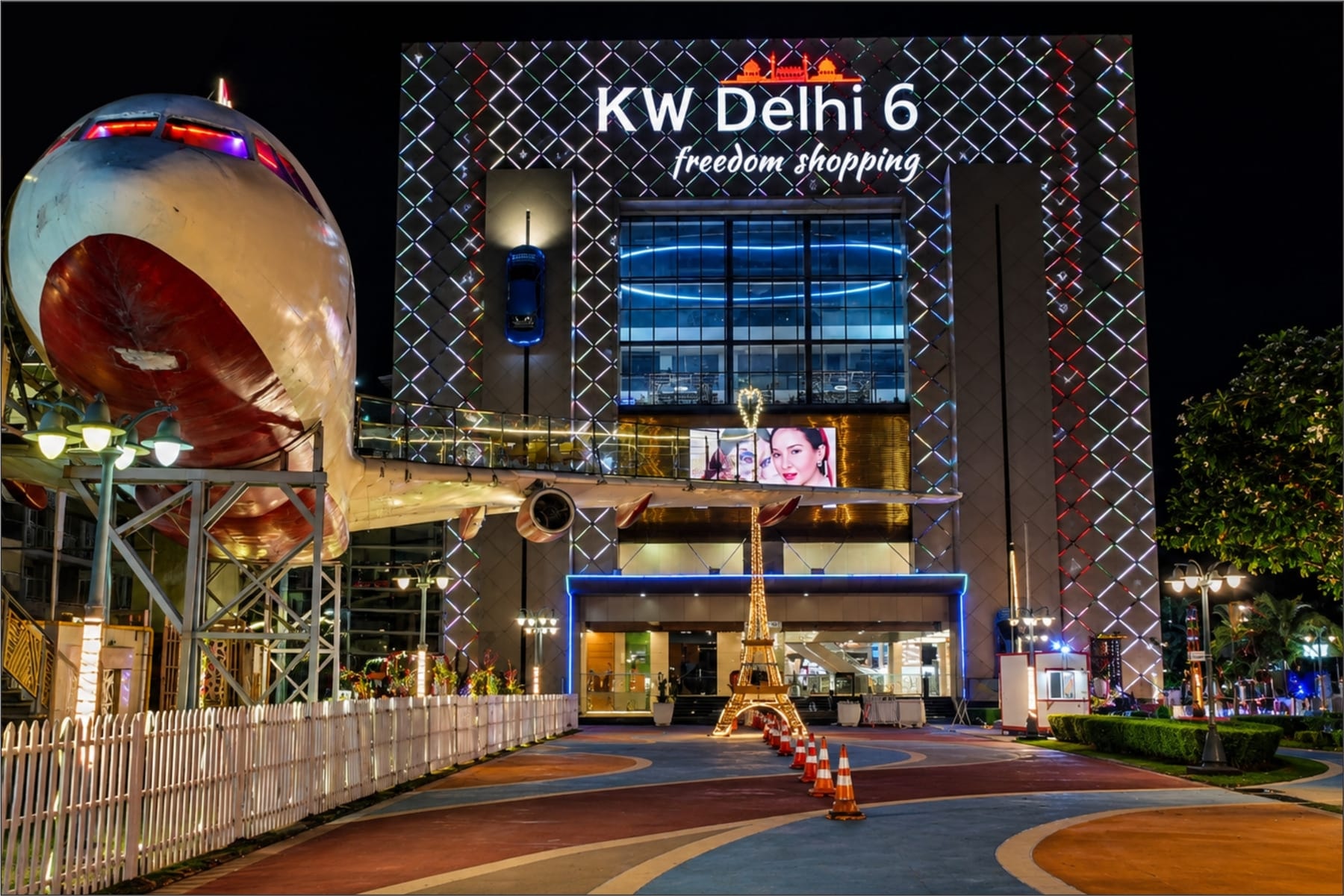 KW Delhi 6 illuminated night facade with the signature aircraft and Eiffel Tower forecourt